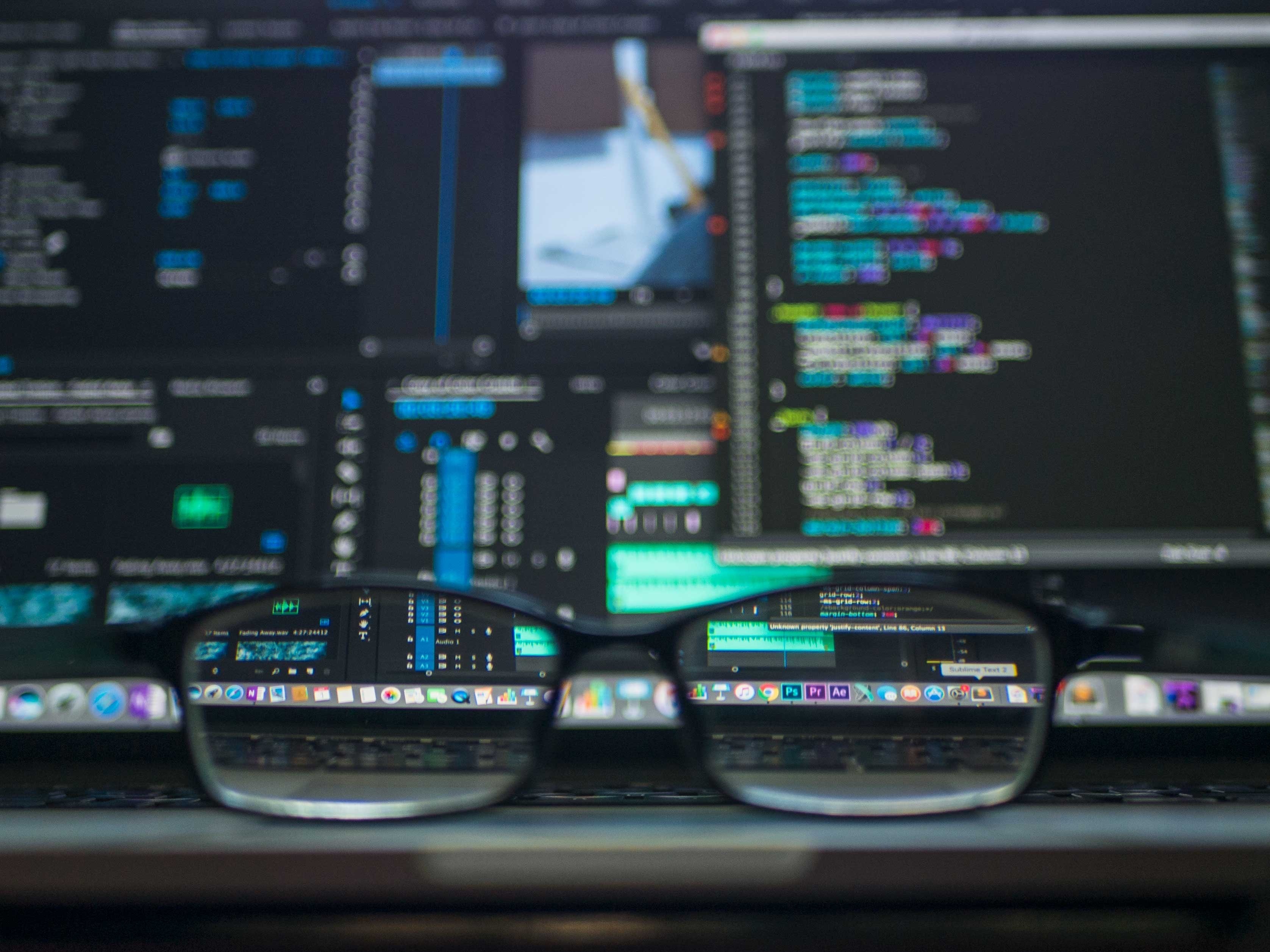 glasses in front of multiple computer screens, comparing moodle hosting provider and self-hosting